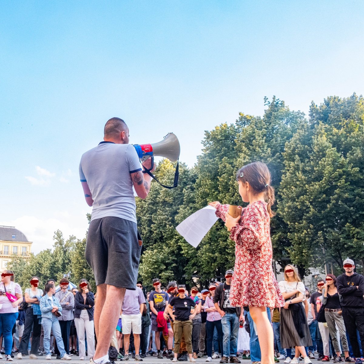 Passage de témoin Une enfant fait passer les notes du discours à un orateur au mégaphone fasse à une foule